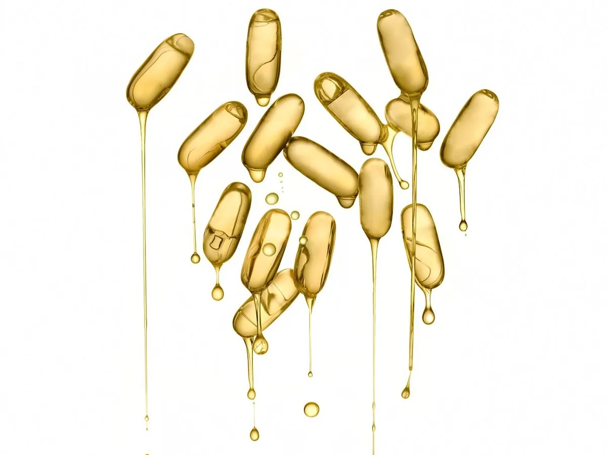 Golden supplement capsules on a light background