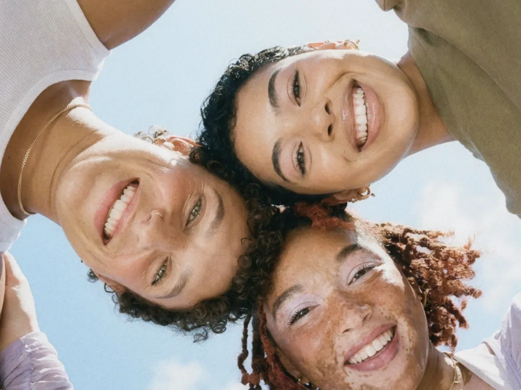 Three young friends smiling together outdoors